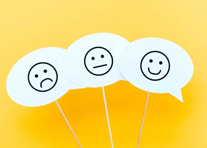 Three word bubbles on yellow background, each with a simply drawn face. One is unhappy, one is happy, and one is neither.