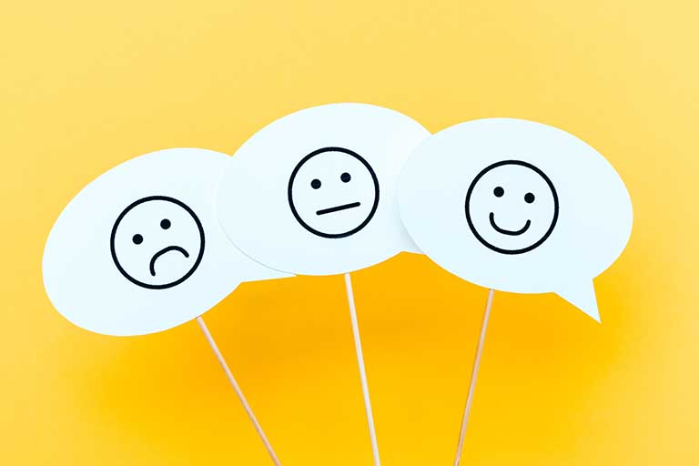 Three word bubbles on yellow background, each with a simply drawn face. One is unhappy, one is happy, and one is neither.